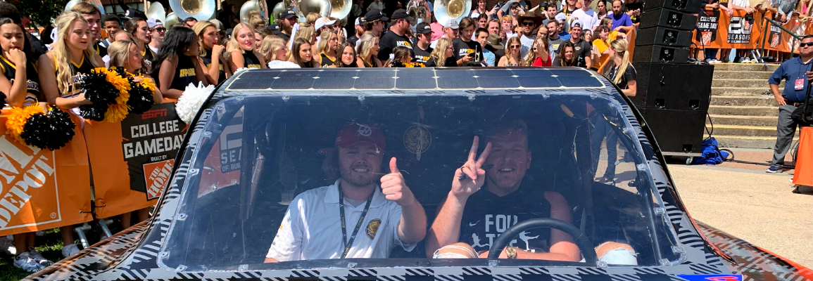 Pat McAfee poses with App State student Patrick Laney inside the ROSE solar vehicle