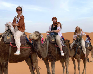 Abbey Metcalf (middle) rides a camel in the Sahara Desert while in Morocco